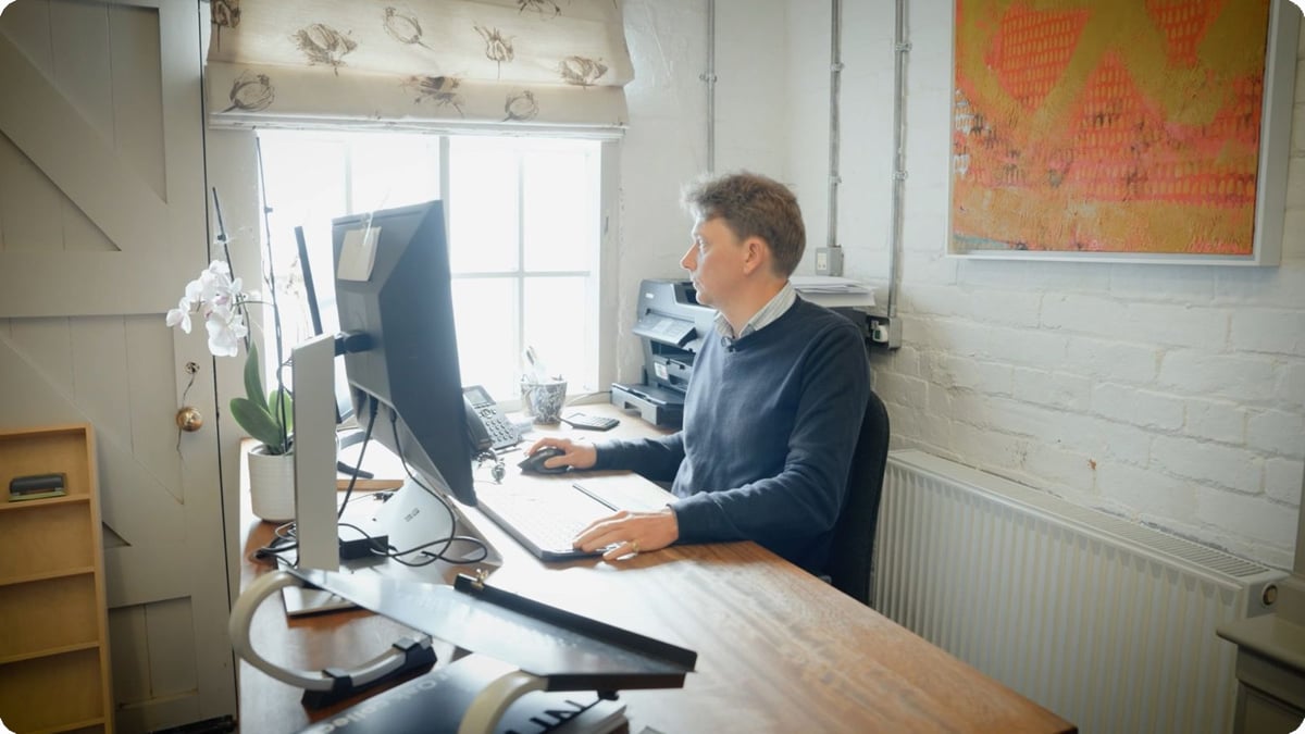 A man seated at a desk, focused on his computer screen
