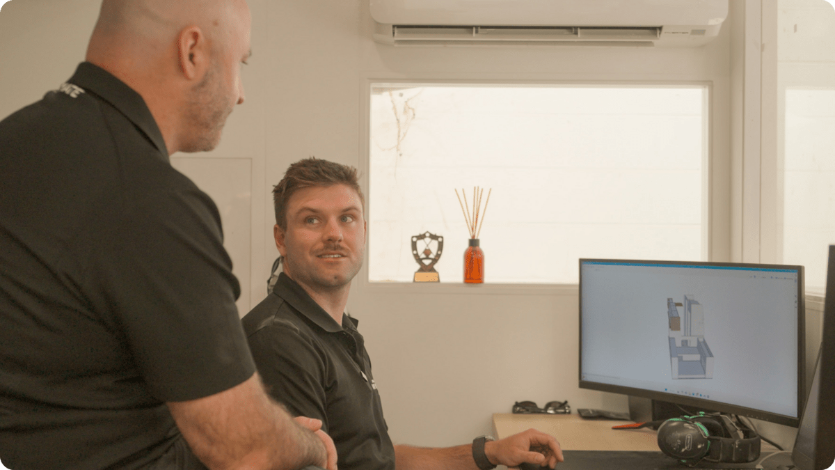 Two men seated at a desk working on a computer